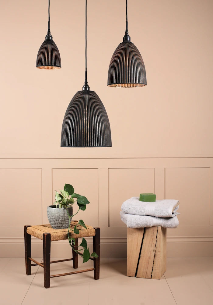 Cluster of 3 large black and gold ribbed glass bathroom pendant lights switched off with plant and towels 