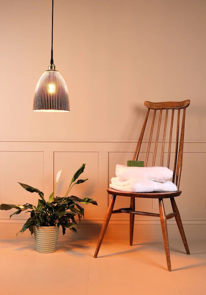 Black and gold bell shaped ribbed glass bathroom pendant light with plant and wooden chair 