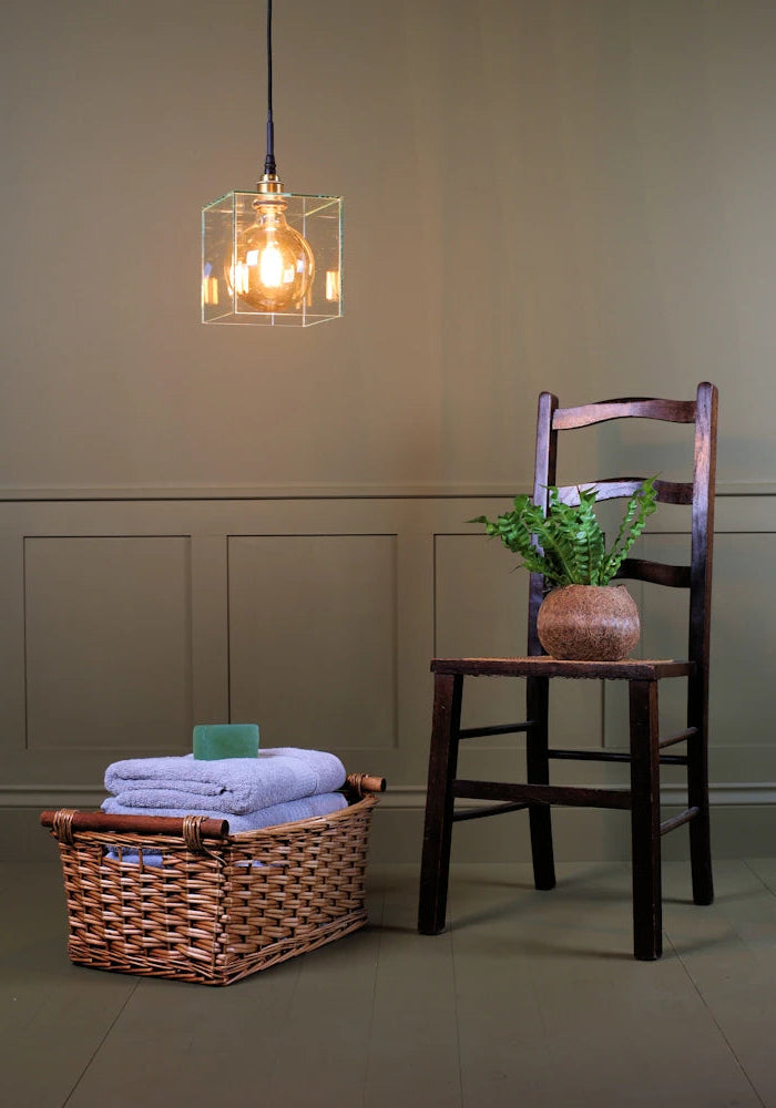 Square clear glass bathroom pendant light with wooden chair, plant and towels 