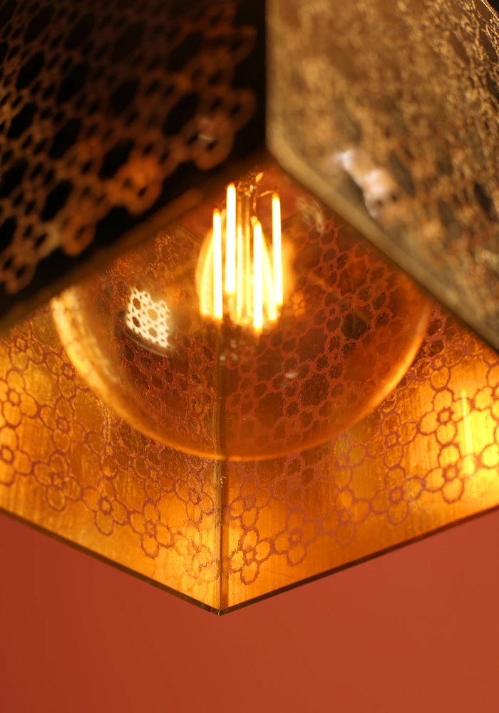 Close up of large square Moroccan patterned gold bathroom pendant light and light bulb.