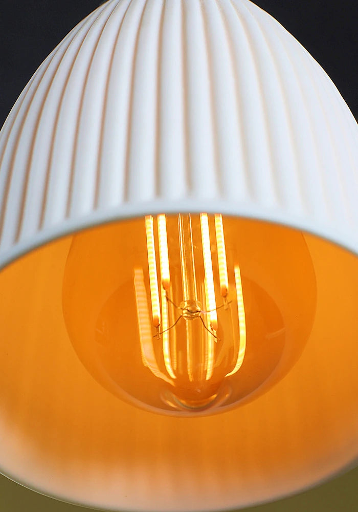 Close up of porcelain bathroom pendant light with Edison light bulb.