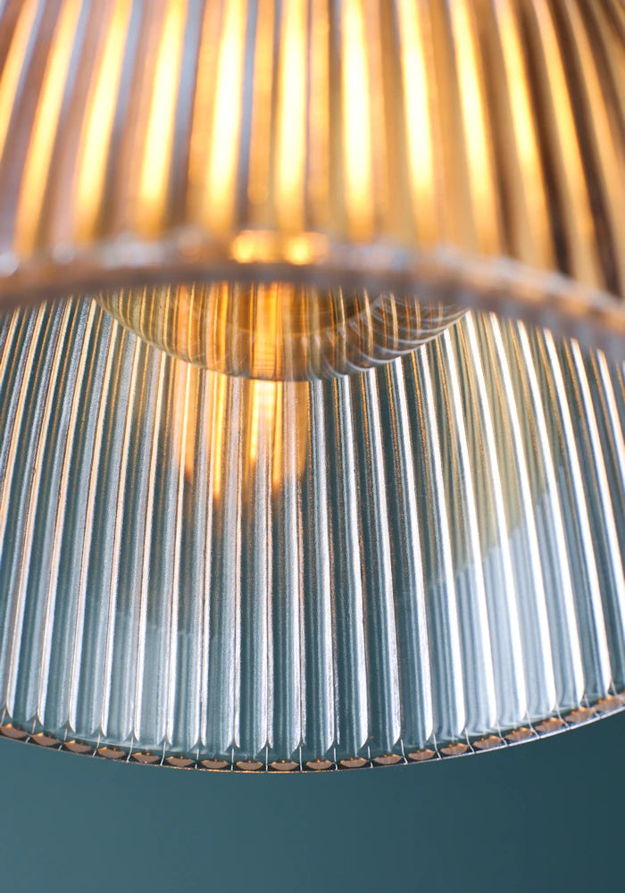 Close up of light bulb in medium size bell shaped ribbed glass bathroom pendant light.