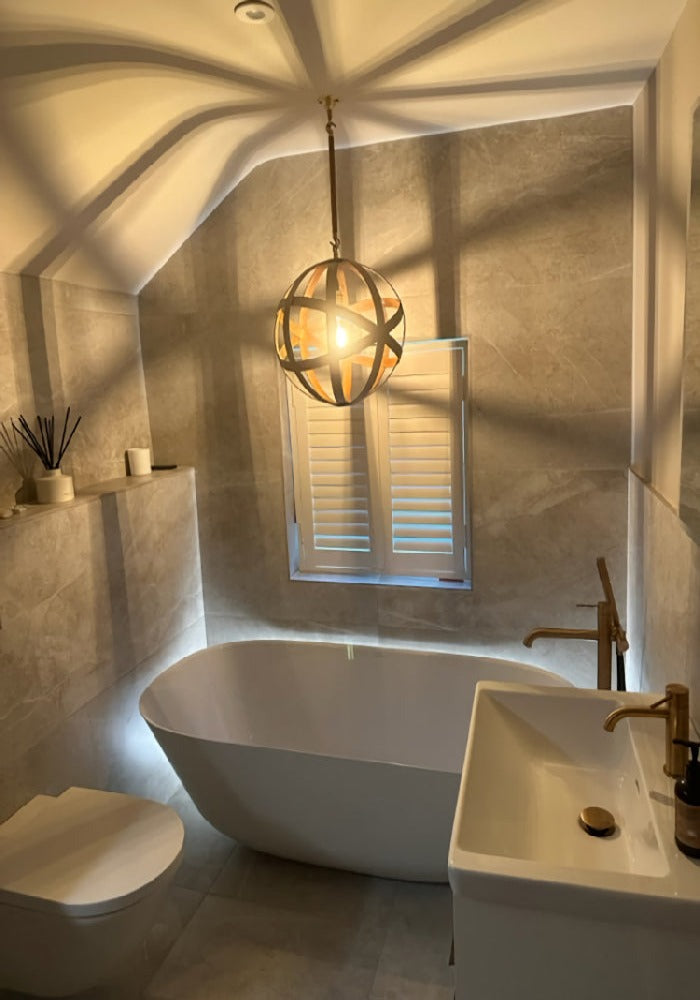 Orbital industrial style bathroom pendant light over bath casting shadows.