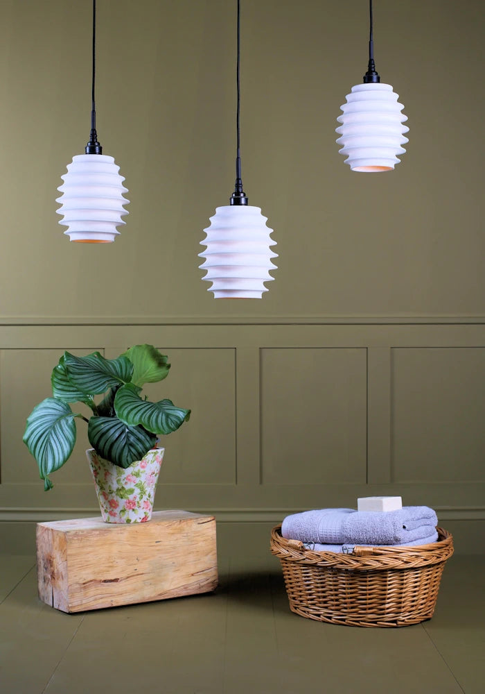 Concertina style porcelain cluster bathroom pendant light switched off with plant and basket of bath towels