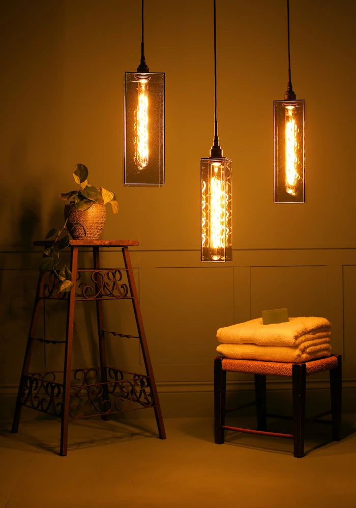 3 way large rectangular smoked glass cluster bathroom pendant light casting shadows, stool with plant, bath towels