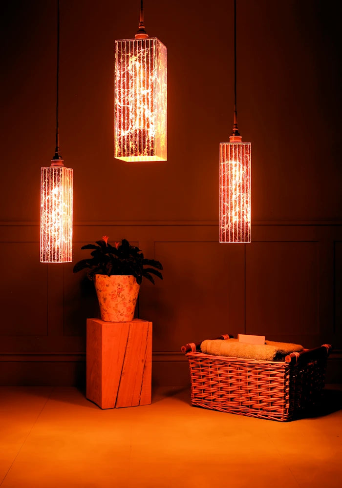 Large triple rectangular copper leaf cluster bathroom pendant light casting shadows, plant and basket of bath towels. 