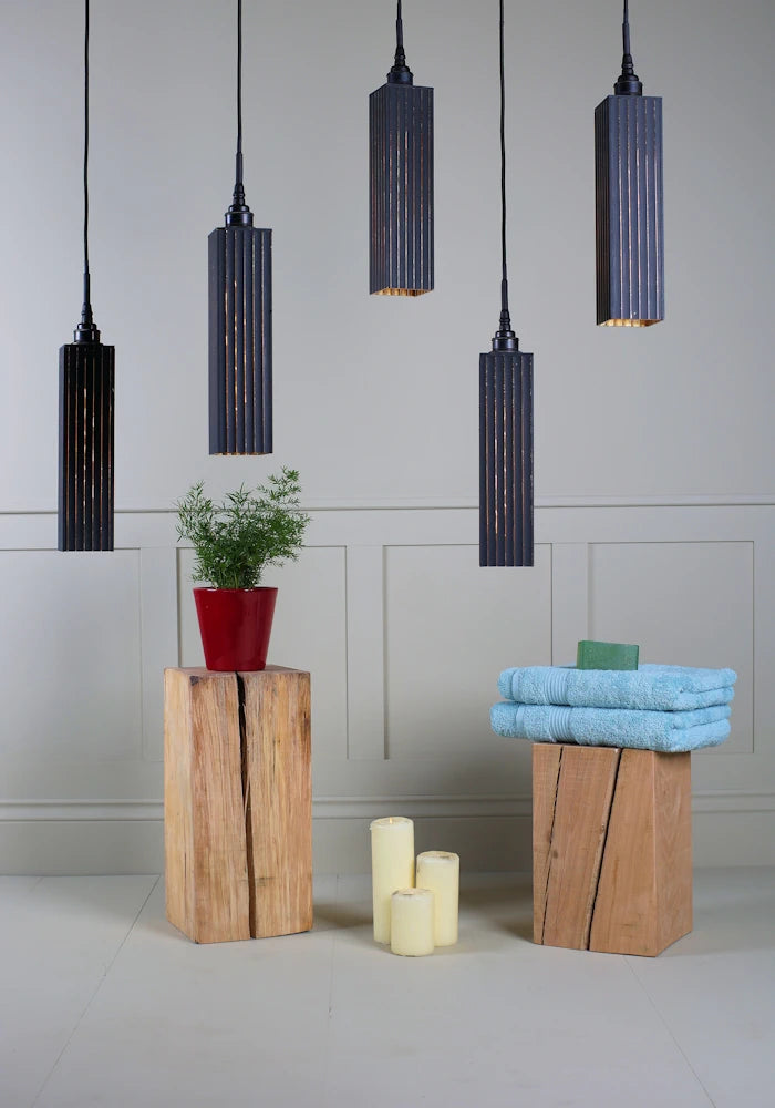 5 black and gold cluster bathroom pendant light switched off with plant, candles and bath towels.