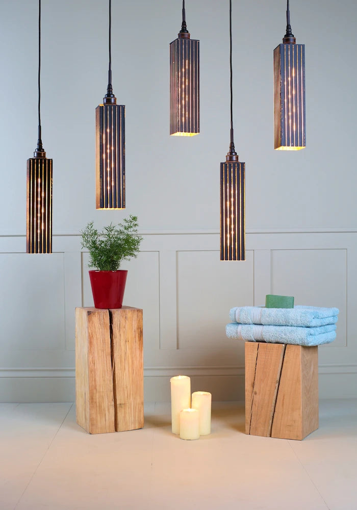 5 black and gold cluster bathroom pendant light with plant, candles and bath towels.