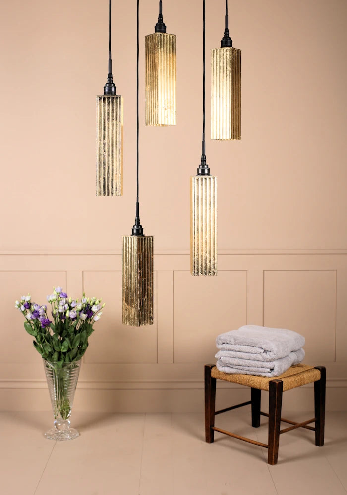 5 cluster gold leaf rectangular bathroom pendant lights switched off with vase of flowers and bath towels.