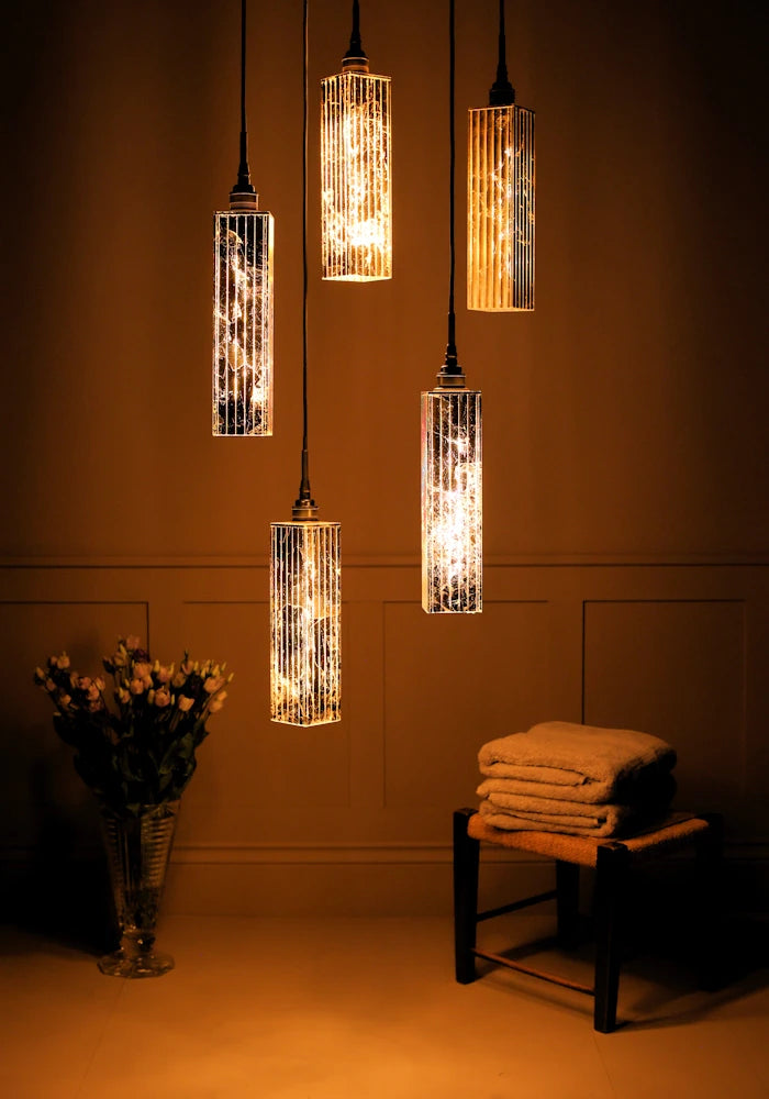 5 cluster gold leaf rectangular bathroom pendant lights with vase of flowers and bath towels.