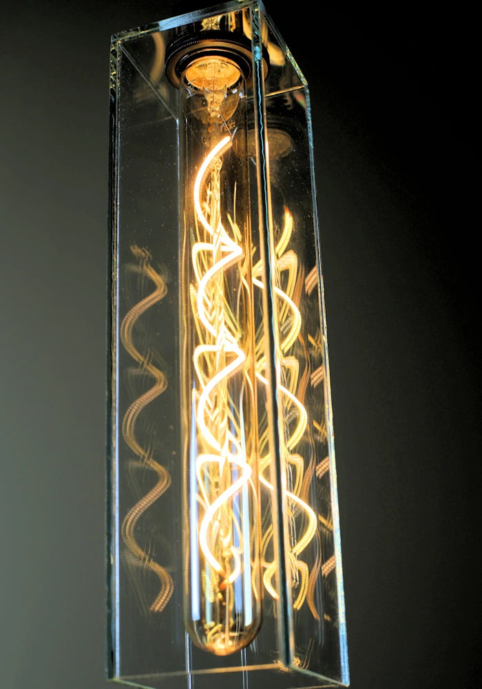 Close up of warm led spiral filament reflecting in glass light shade.