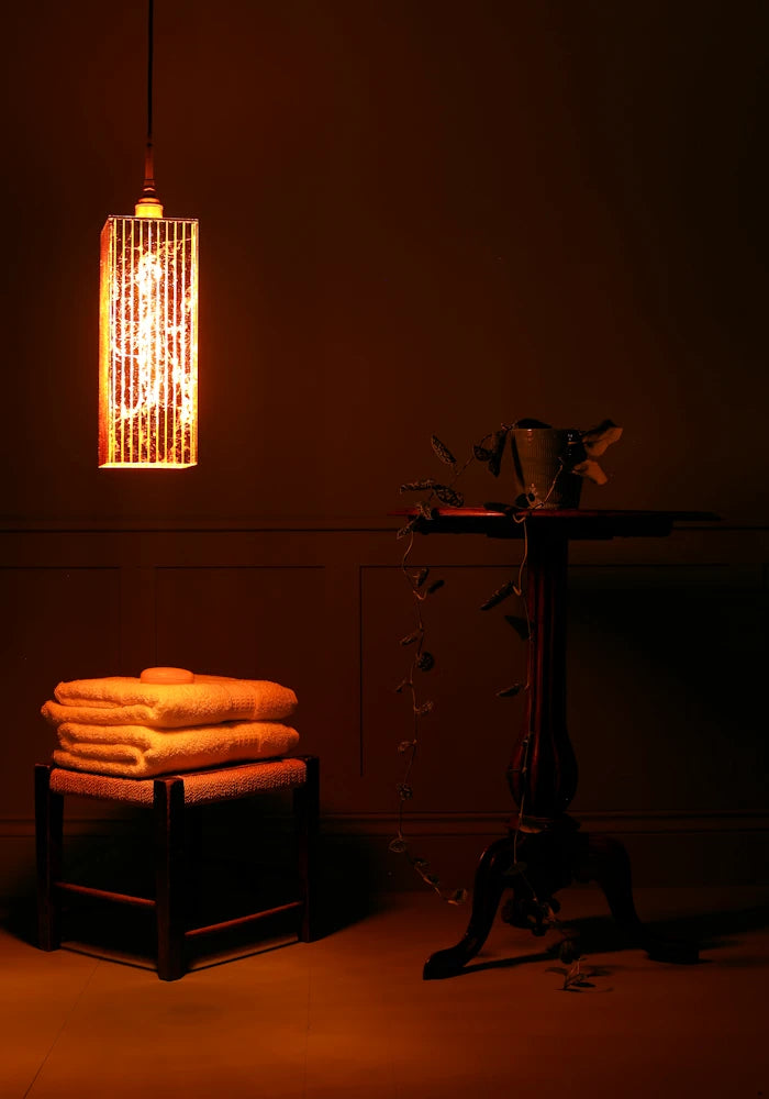 Large rectangular copper lead bathroom pendant light, bath towels and ornate table.