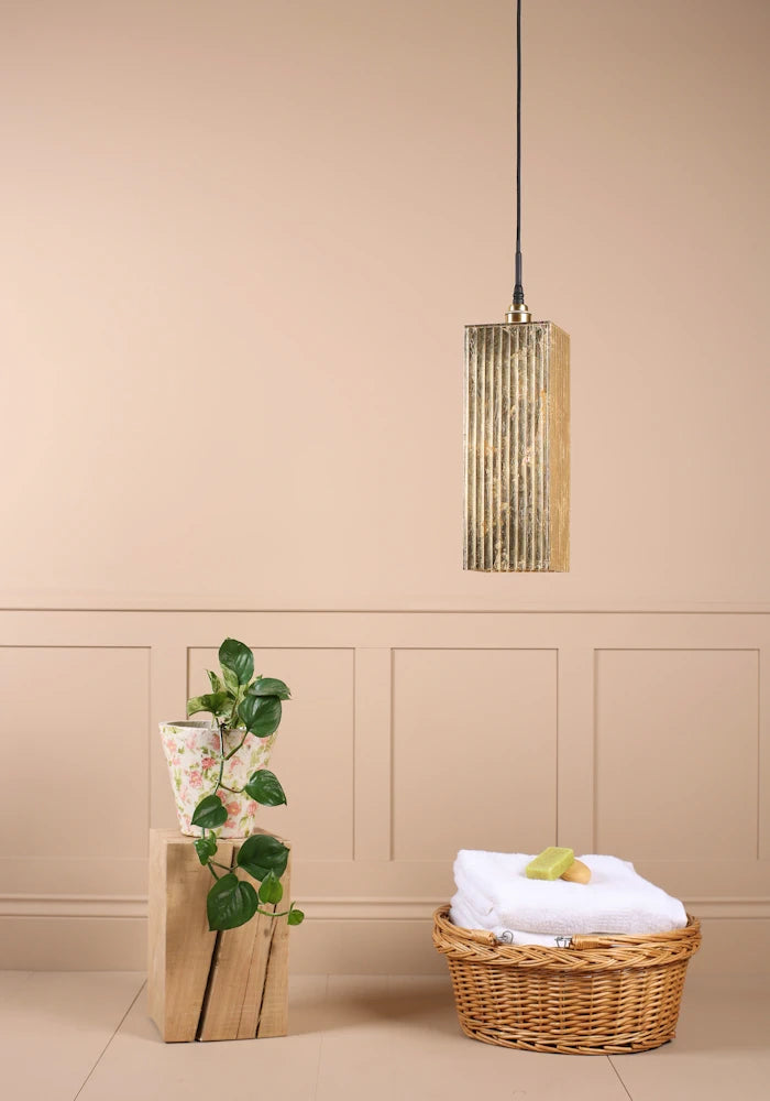 Large rectangular gold leaf bathroom pendant light switched off with plant and bath towels in basket.