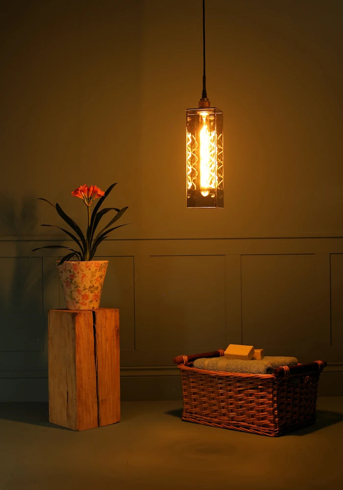 Elongated rectangular smoked glass bathroom pendant light casting shadows, plant, wooden basket and bath towels.