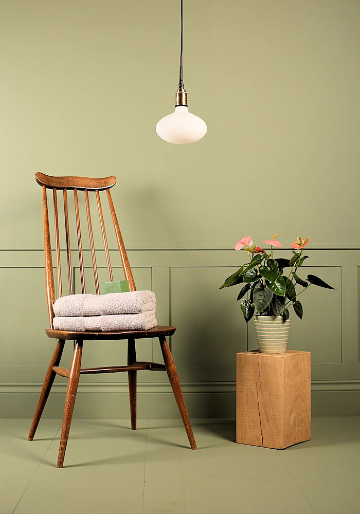 Tala Oval bathroom pendant light switched off, wooden chair and plant.