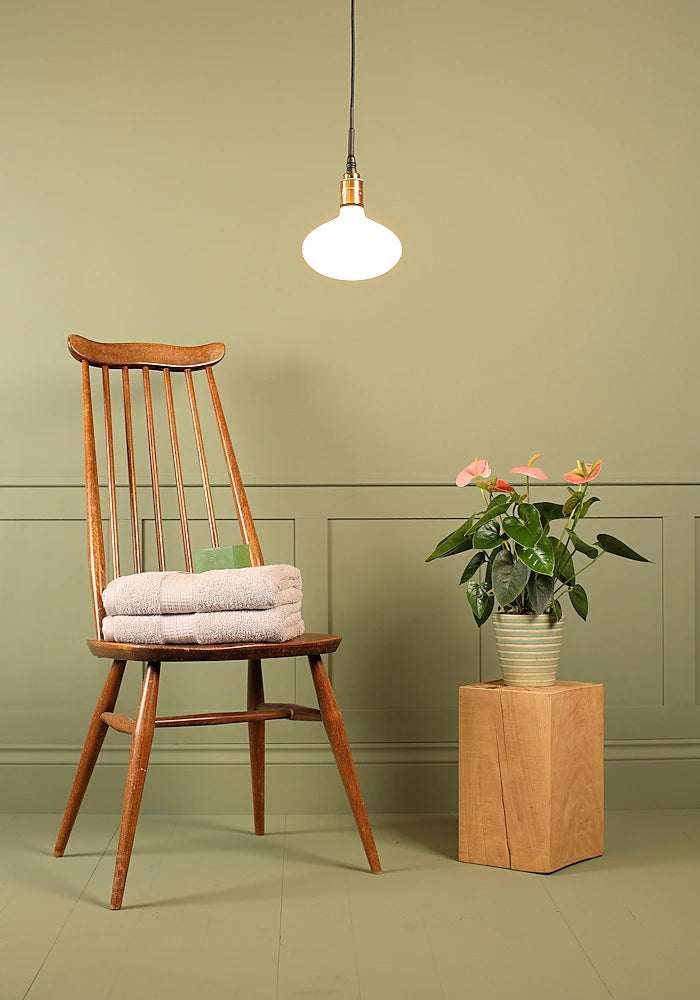 Tala Oval bathroom pendant light, wooden chair and plant.