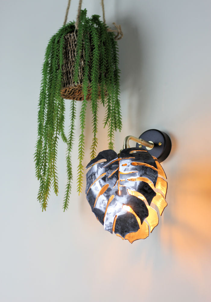 Industrial-style metal bathroom wall light with plant.